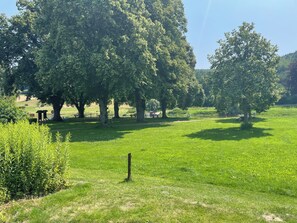 A park with large trees, grassy areas, and picnic tables.