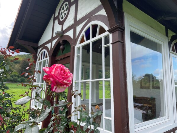 A traditional building with a large window and a rose in the foreground.