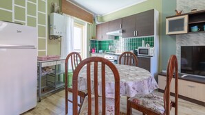Een praktische keuken met een koelkast, magnetron en een eethoek met een tafel en stoelen.