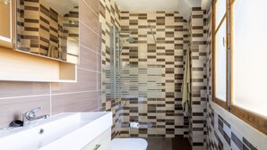 Een badkamer met een douche, toilet en wastafel.