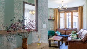 Een woonkamer met een bank, een bijzettafeltje, een spiegel en een vaas met bloemen.