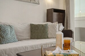 A hotel room with a sofa, a small table with a candle and a glass, and a window with curtains. - Apartment 'Reserva Del Higuerón' with Sea View, Wi-Fi and Air Conditioning (Fuengirola)