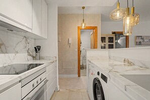 Eine moderne Küche mit Einbauwaschmaschine, Herd und einer Pendelleuchte.