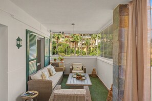 A balcony with wicker furniture, a table, and a view of a building with balconies. - Apartment 'Reserva Del Higuerón' with Sea View, Wi-Fi and Air Conditioning (Fuengirola)