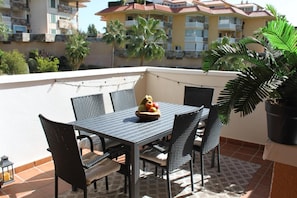 A balcony with a table, chairs, a fruit bowl, and a potted plant. - Apartment 'Reserva Del Higuerón' with Sea View, Wi-Fi and Air Conditioning (Fuengirola)