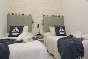 A hotel room with two beds, each with a sailboat pillow, a lamp, and a map wallpaper. - Apartment 'Reserva Del Higuerón' with Sea View, Wi-Fi and Air Conditioning (Fuengirola)