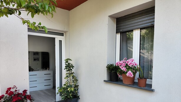 Ein sauberes, modernes Äußeres mit einer gefliesten Terrasse, einer weißen Wand und einem Fenster mit Rollo.