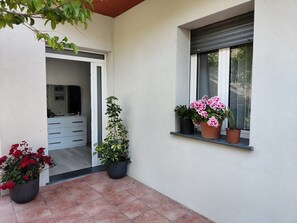 A clean, modern exterior with a tiled patio, a white wall, and a window with a roller blind.