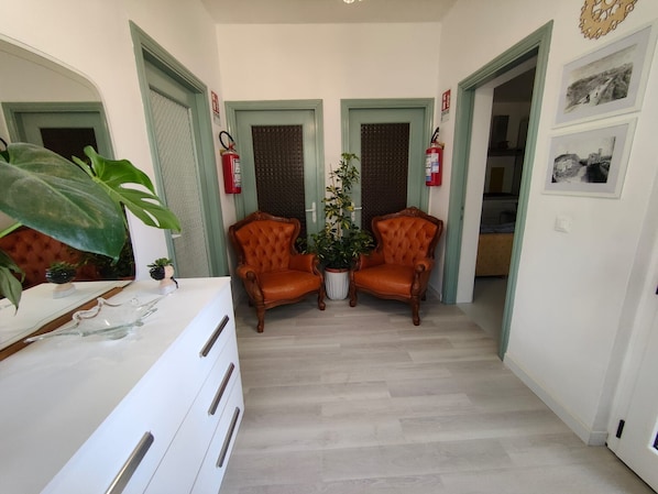 A hallway with two leather armchairs, a white dresser, and a potted plant.