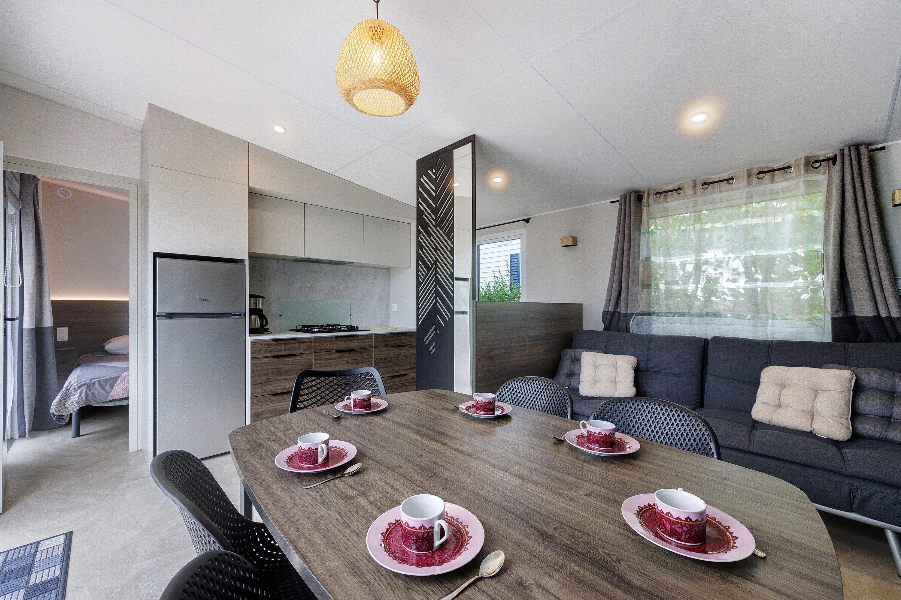 A modern, compact living space with a dining area, kitchenette, and a sofa with cushions.