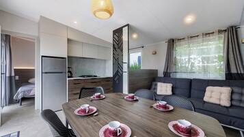 A modern, compact living space with a dining area, kitchenette, and a sofa with cushions.