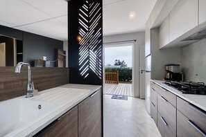 Una cocina moderna con encimera blanca, pileta de acero inoxidable y cocina integrada.