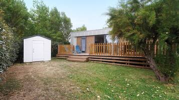 A single-story building with a deck, a small shed, and a grassy yard.
