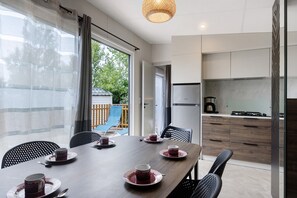 Un comedor con una mesa lista para cuatro, una cocina con electrodomésticos modernos y vistas al exterior.