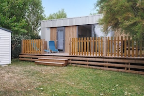 Una cabana moderna amb terrassa, porta corredissa de vidre i zona d'estar exterior petita.