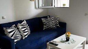 Un salon avec un canapé bleu, une table basse blanche et un miroir au mur.
