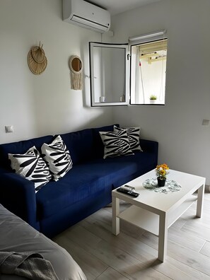 Ein Wohnzimmer mit einem blauen Sofa, einem weißen Couchtisch und einem Spiegel an der Wand.