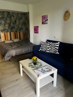Ein modernes Wohnzimmer mit einem Bett, einem blauen Sofa, einem weißen Couchtisch und einer Wand mit abstrakten Kunstwerken.
