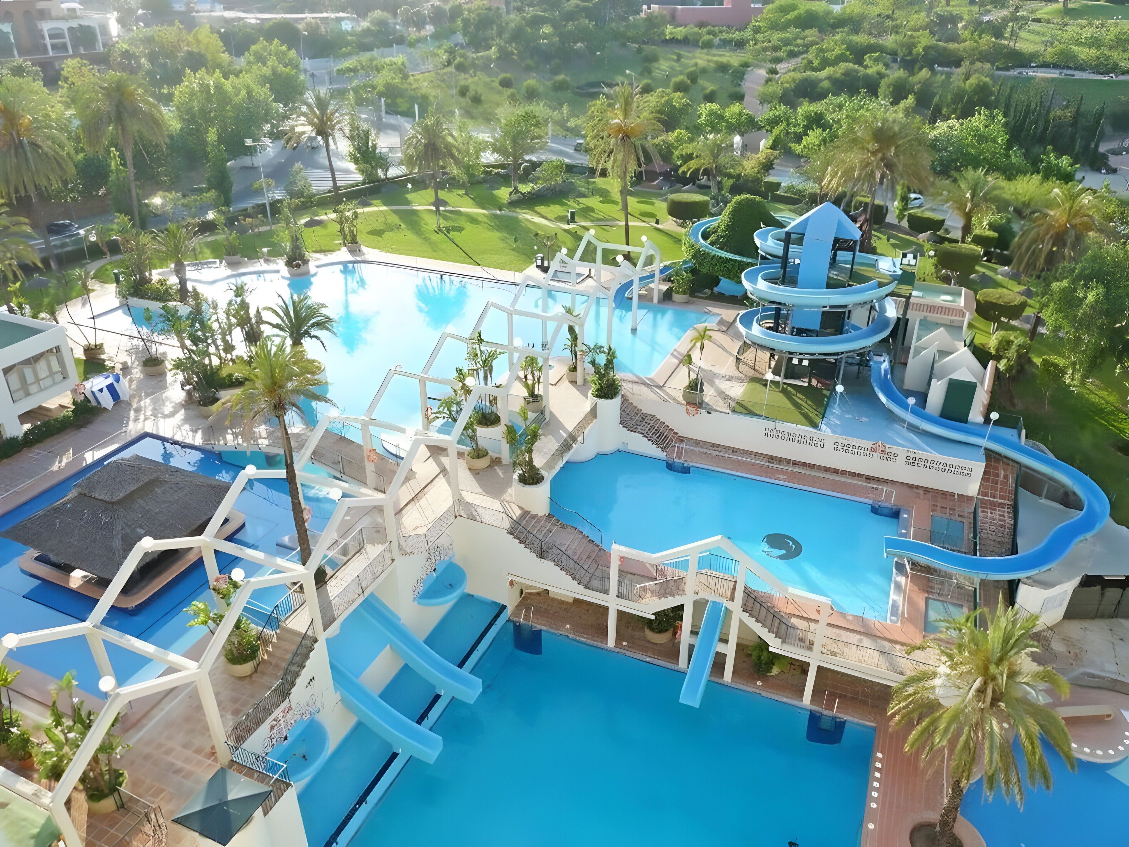 Una gran piscina con múltiples toboganes y una zona de parque acuático.