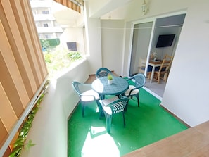 Ein Balkon mit Tisch und Stühlen, einem Blumentopf und Blick auf die Außenansicht des Gebäudes.