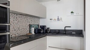 Una cocina moderna con encimera negra, armarios blancos y salpicadero con diseño moteado.