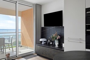 Un baño moderno con salpicadero de mármol negro, un lavamanos blanco y un pequeño jarrón blanco con flores.