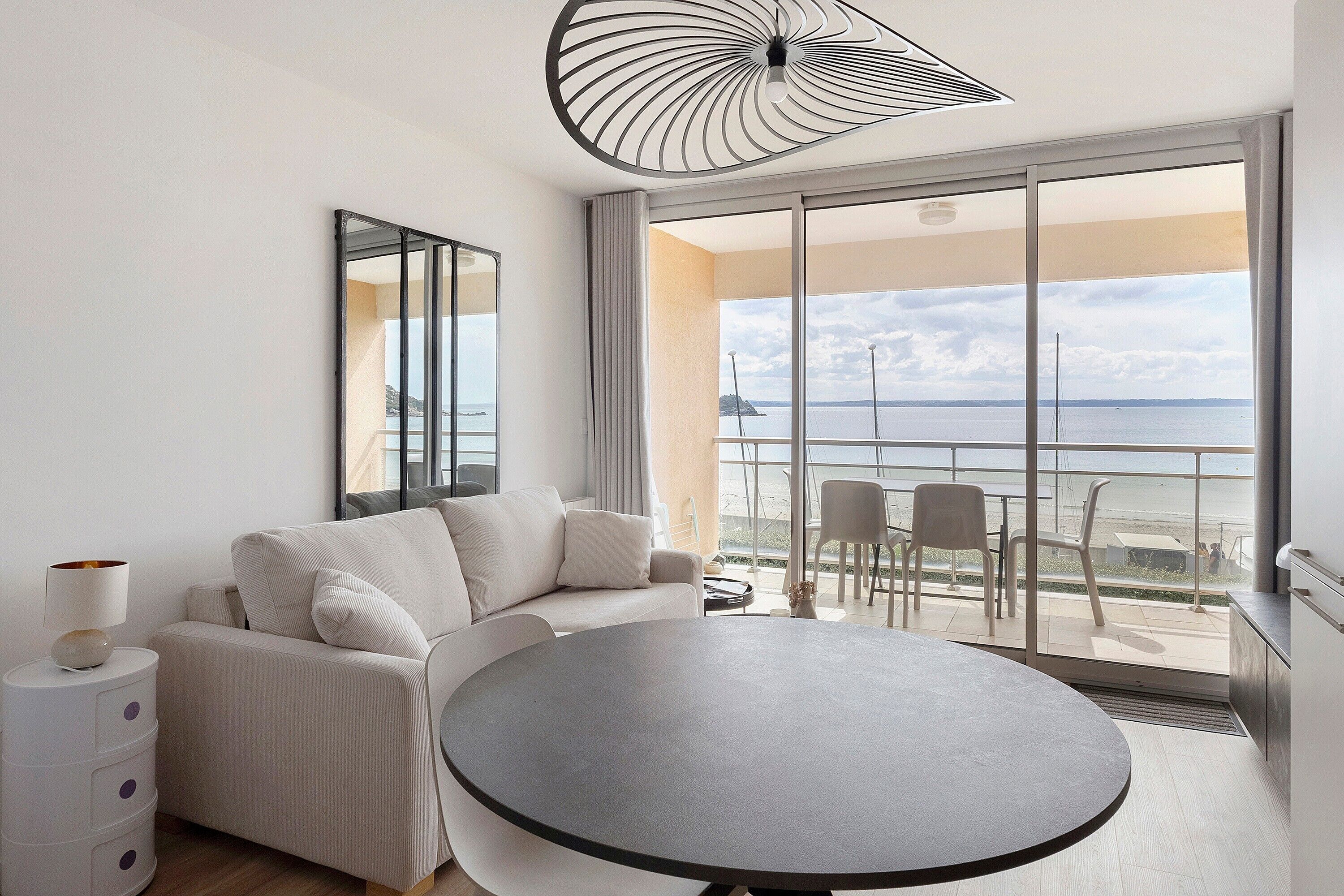 Une chambre d’hôtel moderne avec un balcon, une table ronde et un canapé.