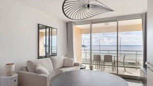Una habitación de hotel moderna con balcón, una mesa redonda y un sofá.