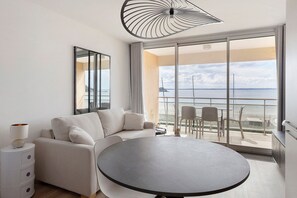 Une chambre d’hôtel moderne avec un balcon, une table ronde et un canapé.