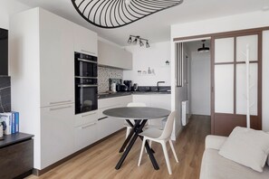 Una cocina moderna con armarios blancos, una mesa redonda de comedor y un horno empotrado.