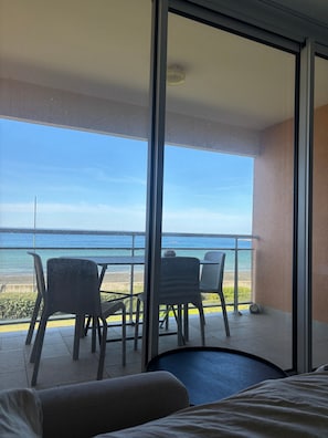 Un balcó amb vista al mar, una taula amb caires i un llit.