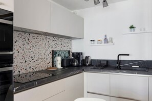 A modern kitchen with a black countertop, white cabinets, and a backsplash with a speckled pattern.