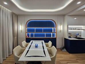 Ein modernes Hotelzimmer mit Essbereich, einer blauen Wand als Gestaltungselement und einer Küchenzeile.