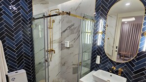 Ein modernes Badezimmer mit einer Duschkabine, einem weißen Waschbecken und einer Duschfläche mit Marmorfliesen.