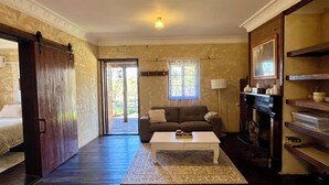Una habitación con sofá, mesa de centro, chimenea y puerta que da a un balcón.