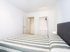 A bedroom with a bed, a nightstand, a dresser, and a door leading to another room. - CHL Apartamento Confort G mar Tenerife (Güímar)