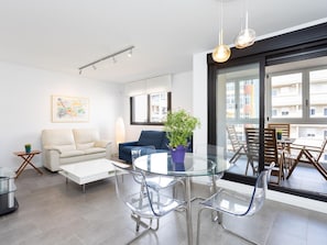 A modern living room with a glass dining table, clear chairs, a sofa, a coffee table, and a potted plant. - CHL Apartamento Confort G mar Tenerife (Güímar)