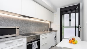 Una cocina moderna equipada con microondas, horno, pileta y lavadora.