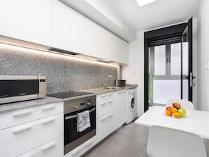 A modern kitchen with a microwave, oven, sink, and washing machine. - CHL Apartamento Confort G mar Tenerife (Güímar)