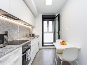 A modern kitchen with a built-in oven, a microwave, and a granite countertop. - CHL Apartamento Confort G mar Tenerife (Güímar)