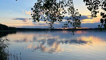 Un lac paisible où se reflètent les arbres et où le ciel est dégagé.