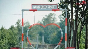 Um portão em formato de coração com uma placa acima que diz 'NAMIR GREEN RESORT'.