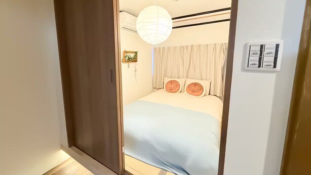A bedroom with a bed, a hanging light fixture, a wardrobe, and a wall-mounted control panel. - (千本南)Doraemon House in Osaka | 4 Min to Subway | Tea Room | Easy Airport Access (Osaka)