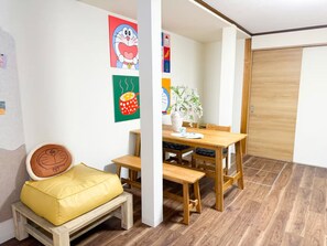 A room with a wooden bench, a dining table with chairs, a vase with flowers, and wall art. - (千本南)Doraemon House in Osaka | 4 Min to Subway | Tea Room | Easy Airport Access (Osaka)