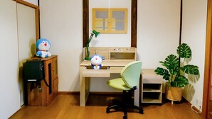 A room with a wooden desk, a green chair, a lamp, a potted plant, and a shelf with figurines. - (千本南)Doraemon House in Osaka | 4 Min to Subway | Tea Room | Easy Airport Access (Osaka)