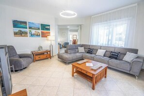 Ein Wohnzimmer mit grauem Sofa, einem Holztisch und einem Fernseher.