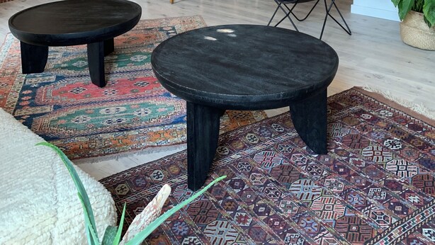 Un espace de vie de style loft comprenant une table à manger, deux petites tables rondes noires, un escalier et une cuisine en arrière-plan.