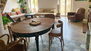 Un salon chaleureux avec une table ronde en bois, des carreaux de sol hexagonaux, un canapé et une bibliothèque.