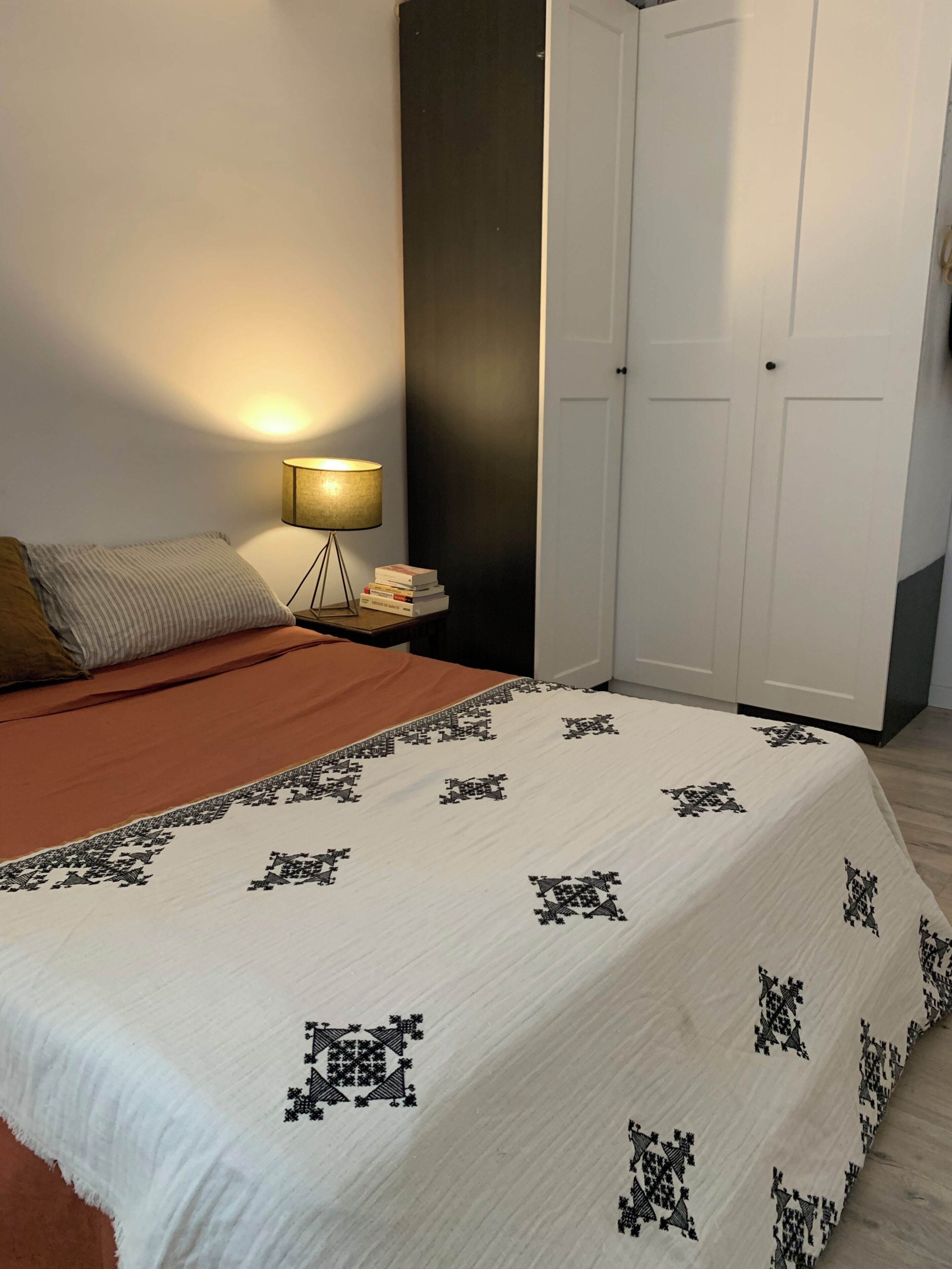 Une chambre à coucher avec un lit, une lampe de chevet, une table de chevet et une armoire.