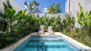 A rectangular pool with clear blue water, surrounded by lush greenery and two lounge chairs. - Art Villa by Betterplace (Ubud)